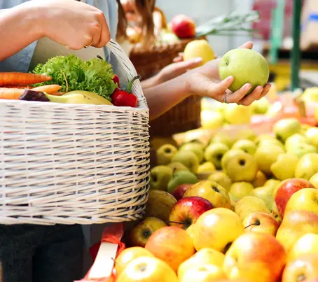 Une cliente regarde les pommes chez le primeur